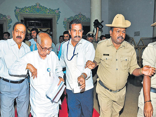 Historian Prof M Chidananda Murthy is escorted out of the Banquet Hall of the Vidhana Soudha after a protest by him and others led to chaos during the Devara Dasimayya  Jayanti celebration on Wednesday. DH&#8200;photo