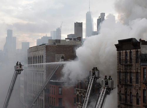 New York City firefighters on ladders spray water at the scene of a fire and a partial building collapse in the East Village neighborhood of New York. AP photo