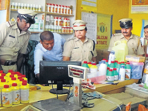 Additional Superintendent of Police Kala Krishnamurthy and other officials examine the CCTV camera footage at a shop at Bettadapura, in Periyapatna taluk, on Saturday. DH PHOTO