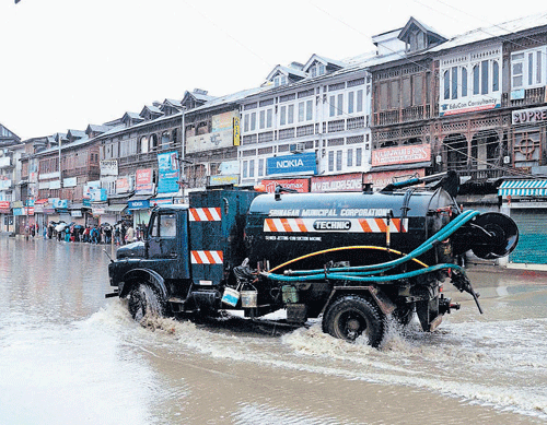 water all around: A city municipal corporation vehicle passes through a waterlogged road after the valley received heavy rainfall, in Srinagar on Sunday. pti