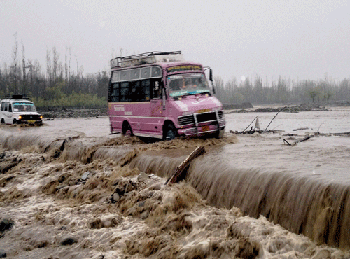 Vehicles pass through submerged bridge in a flooded Larkipora area in Anantnag, south Kashmir on Sunday. PTI Photo