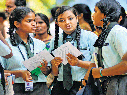 All set: Students engage in last-minute discussions outside an examination centre in  Bengaluru on the first day of the SSLC exams on Monday. A mother prays for the success of her child in the exams. DH photos