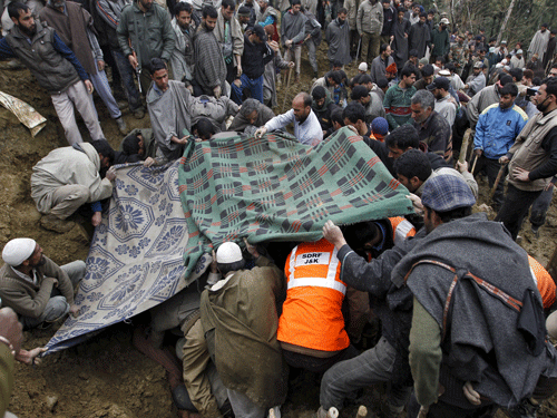 Villagers and rescue workers use blankets to cover the bodies of victims amongst the rubble after a hillside collapsed onto a house at Laden. Reuters Photo