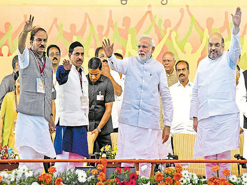 Prime Minister Narendra Modi waves to the crowd during a BJP rally at the National College grounds in Bengaluru on Friday. BJP National vice president B S Yeddyurappa, Union Minister Ananth Kumar, State president Pralhad Joshi, national president Amit Shah, leaders L K Advani, Jagadish Shettar, K S Eshwarappa and others are seen. DH&#8200;Photo