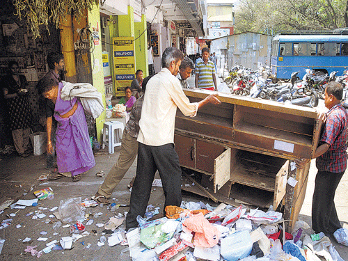 human touch: BBMP workers lend a helping hand to vendors in safely removing their belongings from footpaths at the Jayanagar Shopping Complex during an eviction drive on Thursday. DH photo