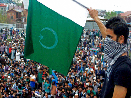 A masked supporter of Chairman of Hardline Faction of Hurriyat Conference Syed Ali Shah Geelani waves Pakistani flag during a rally in Srinagar on Wednesday. PTI Photo