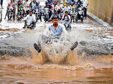 rough weather: A man rides his bike through a waterlogged road in Chennai on  Wednesday. DH Photo