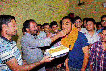 Super 30 founder Anand Kumar offers sweets to Abhishek in Patna. DH PHOTO