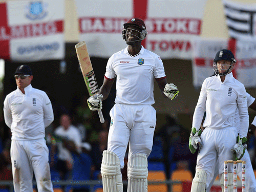 West Indies batsman Jason Holder (C) celebrates his century beside English wicketkeeper Jos Buttler (R) on day five of the first cricket Test match between West Indies and England at the Sir Vivian Richards Stadium in St John's, Antigua on April 17, 2015 AFP PHOTO.