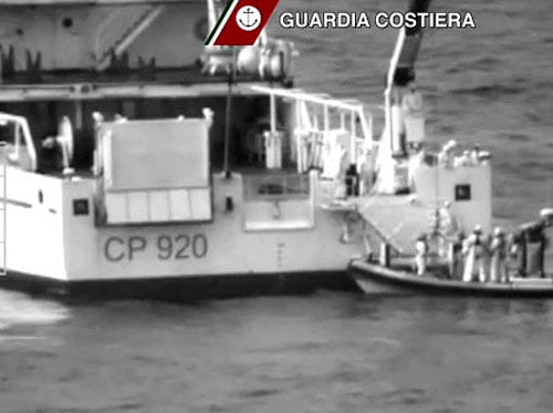 Italian coast guard officers stand on a dinghy beside an Italian coast guard vessel as a massive search and rescue operation is conducted at sea after a boat carrying migrants capsized overnight, in this still image taken from video. Reuters