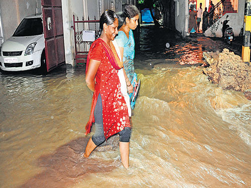 People wade through rainwater in Srinivasa Colony near K H Road on Saturday. DH&#8200;Photo