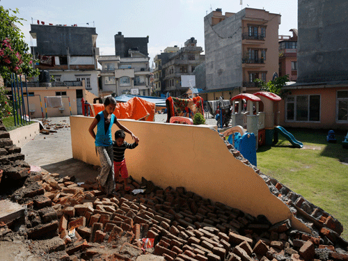A young girl walks with a boy over a collapsed school playground in Kathmandu, Nepal, Monday, April 27, 2015. A strong magnitude 7.8 earthquake shook Nepal's capital and the densely populated Kathmandu Valley on Saturday, causing extensive damage with toppled walls and collapsed buildings. AP Photo.