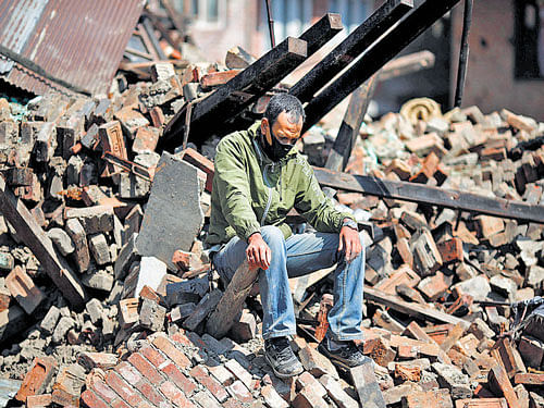 A man sits on the rubble of his damaged house in Bhaktapur, Nepal, on Monday. Reuters