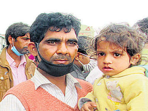 Two-year-old Aryaraj and his father Mukesh Jaiswal await a bus ride to Bihar.  Sagar Kulkarni/ DH photo