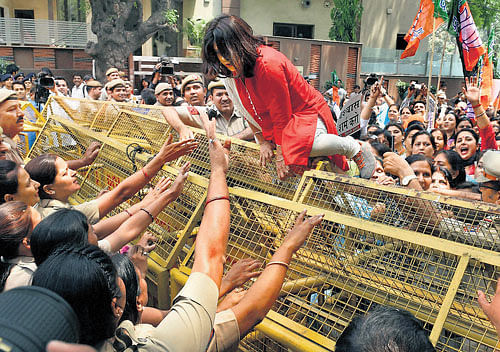 Flying rage: A BJP Mahila Morcha activist tries to cross the barricades during a protest against AAP leader Kumar Vishwas at Chief Minister Arvind Kejriwal's residence in New Delhi on Tuesday. PTI
