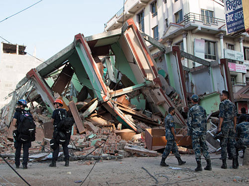 Rescue workers stand beside a building that collapsed in an earthquake in Kathmandu, Nepal. AP photo