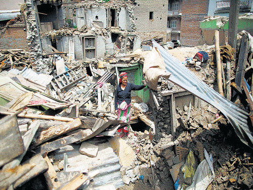 A woman stands on the debris of collapsed houses in Sankhu on Tuesday. REUTERS