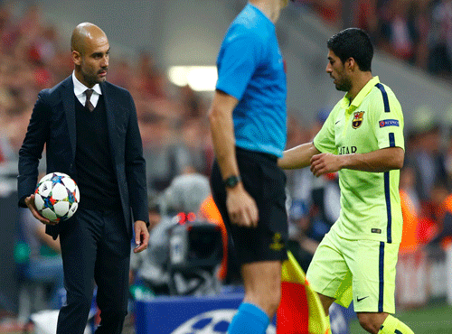 Bayern's head coach Pep Guardiola, left, gives a ball to Barcelona's Luis Suarez during the soccer Champions League second leg semifinal match between Bayern Munich and FC Barcelona at Allianz Arena in Munich. AP photo