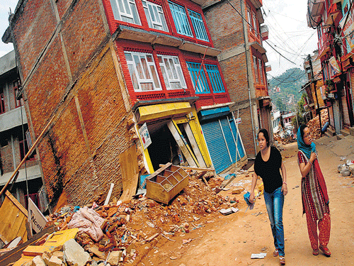 Women walk past a building damaged in earthquake in the Sindhupalchowk district of Nepal on&#8200;Wednesday. REUTERS
