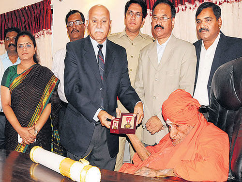 Additional Chief Secretary V Umesh presents the citation and medal of Padma Bhushan award to Siddaganga Mutt seer Dr Shivakumara Swami at a function held at the mutt in Tumakuru on Wednesday. State Protocol Officer Jayavibhavaswamy, Deputy Commissioner Satyamurthy, Additional DC Anuradha, Superintendent of Police Karthikreddy and others are seen. DH PHOTO