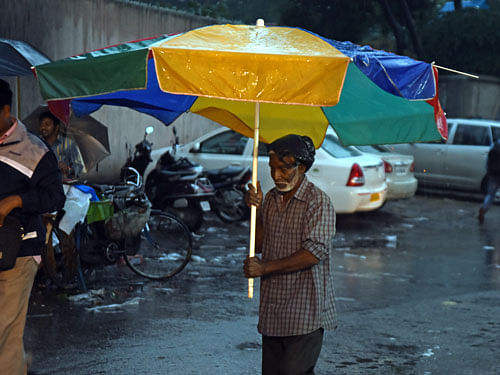 A elderman walks with huge umbrella due to continuous heavy rain at Shivajinagar in Bengaluru on Saturday. DH Photo
