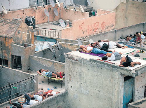 SUMMER BLUES:Men sleep on the roofs of houses to beat the heat in NewDelhi on Friday. AP