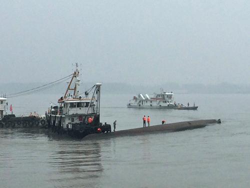 Rescue workers stand on the capsized ship, center, on the Yangtze River in central China's Hubei province. AP Photo