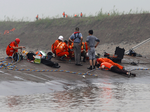 Rescuers listen for reactions from inside a sunken ship as they search for survivors at the Jianli section of the Yangtze River. Reuters Photo