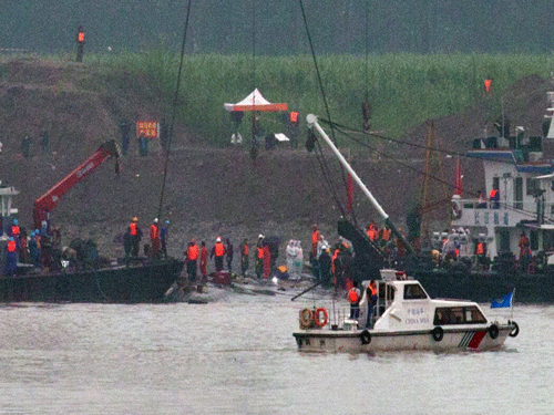 A marine boat patrols past as rescuers work on the capsized ship, center, on the Yangtze River in Jianli county of southern China's Hubei province. AP Photo