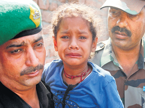 GRIEF:An Army soldier holds the daughter of his colleague who was killed in Thursday's rebel attack in Manipur after his body was brought to Akhnoor inJammuand Kashmir on Sunday. AP