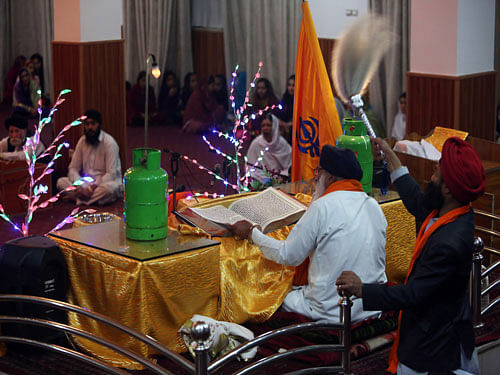 In this Sunday, May 31, 2015, photo, an Afghan Sikh reads the the Guru Granth Sahib, the central religious text of Sikhism, during a service at a Gurdwara, the place of worship for Sikhs, in Kabul, Afghanistan. AP File Photo