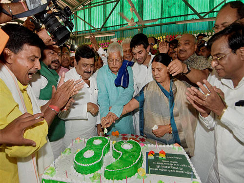 RJD chief Lalu Prasad cutting a cake with his wife Rabri Devi, family members and supporters on his 68th birthday in Patna on Thursday. PTI Photo.