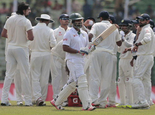 Tamim Iqbal, center, walks back to the pavilion after his dismissal by India's Ravichandran Ashwin during the fourth day of their test cricket match in Fatullah, Bangladesh. AP Photo