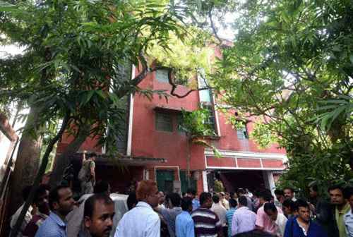 People standing in front of the house where a man was found living with his sister's corpse in Kolkata. PTI Photo