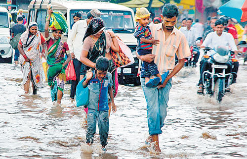 People wade through a waterlogged road in Vijayapura on Monday. DH PHOTO