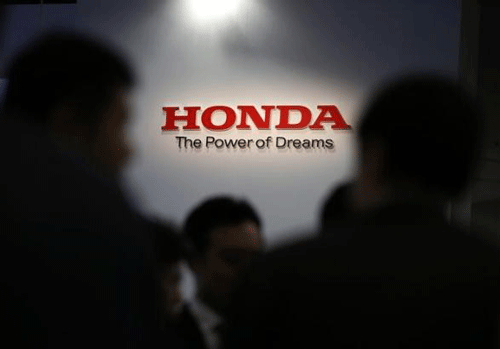 A logo of Honda Motor Co is seen behind journalists after the unveiling event for the company's all-new hybrid sedan ''Grace'' in Tokyo December 1, 2014. REUTERS