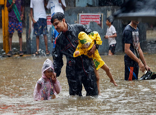 An Indian man carries children and crosses a waterlogged street as it rains in Mumbai, India, Friday, June 19, 2015, AP photo