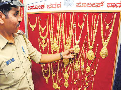 Ashok Nagar police station sub-inspector Ravi K B displays the recovered gold jewellery at the police commissioner's office in the City on Friday.  DH Photo
