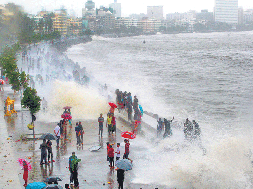 People walk in the rain along the Marine Drive in Mumbai. DH photo