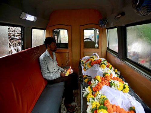 A relative sits inside an ambulance with the body of a victim who died after consuming bootleg liquor at a cremation ground in Mumbai. The toll due to consumption of spurious liquor in Malad area of Mumbai climbed to 97 today with the death of seven more persons in the last 24 hours. Reuters photo