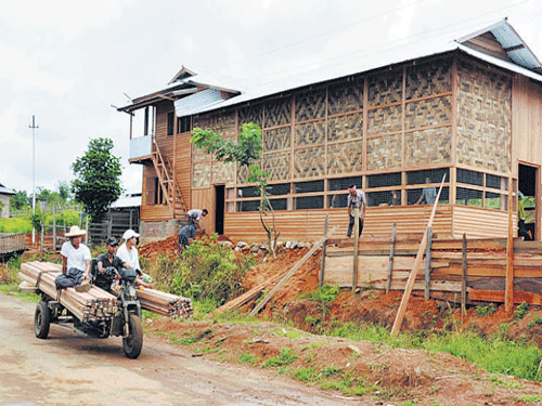 Burmese timber suppliers carrying loads on bike cross past an under-construction community hall in the Holenphai village on the Indo-Myanmar border near Moreh of Chandel district of Manipur. DEEPAK OINAM