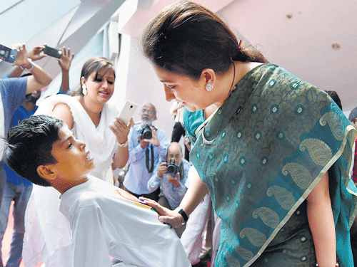 HRD Minister Smriti Irani interacts with a schoolboy performing a yogasana on her arrival for the inauguration of the National Yoga Teachers Conference in New Delhi on Monday. PTI