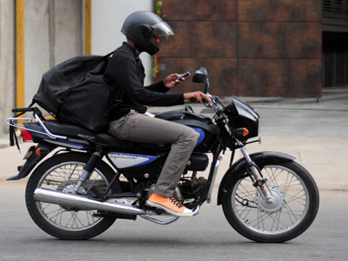 The City traffic police, invoking Section 250 (A) MMVR, r/w Section 177 of the Motor Vehicles Act, said no person, whether driving a four-wheeler or riding a two-wheeler, should use a mobile phone even while waiting at the traffic signal. DH file photo. For representation purpose