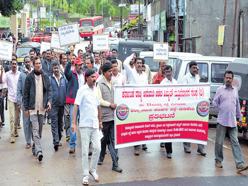 Urging for the fulfillment of various demands, electricity contractors stage a protest in Madikeri on Thursday. DH photo