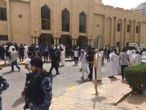 Security forces, officials and civilians gather outside of the Imam Sadiq Mosque after a deadly blast struck after Friday prayers in Kuwait City, Kuwait, Friday, June 26, 2015. There was no immediate claim of responsibility for what appears to be a bombing that targeted the Shiite mosque. AP Photo.