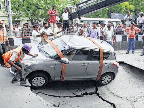 A car is lifted from a road which cracked due to Metro Rail tunnelling construction in Chennai on Friday. DH photo