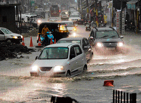 Vehicles move through a water-logged road after heavy rain in Jammu on Monday. PTI
