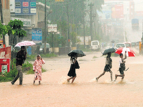 Students cross National Highway-17 at Kottara Chowki in Mangaluru, following incessant rainfall on Thursday. DH photo