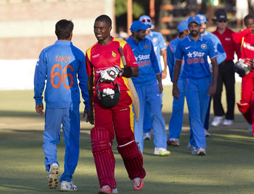 Zimbabwean cricket captain Elton Chigumbura, centre, walks off the pitch after losing to India in their One Day International in Harare, Zimbabwe. AP photo