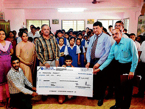 SBI Regional Manager Khadri Gundu Rao hands over a cheque for Rs 1 lakh to St Agnes Special School student Mohammed Fardeen in Mangaluru on Friday. dh photo